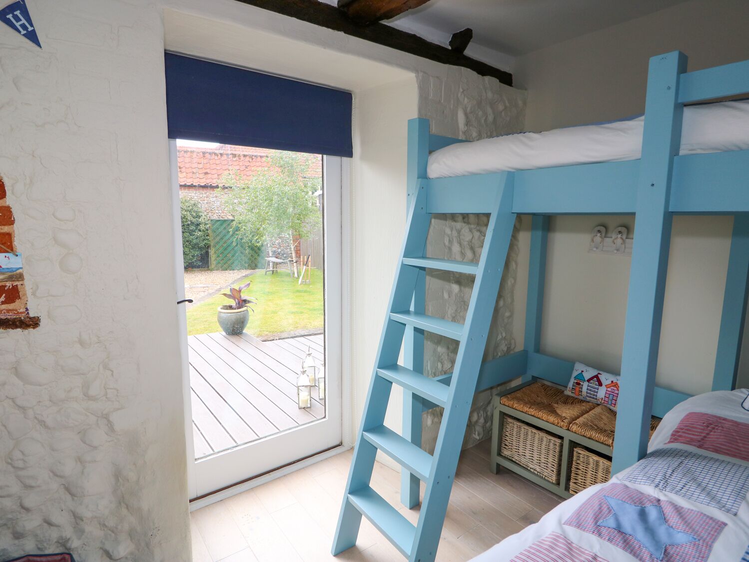 A bedroom with a bunk bed, a window with a view of a garden, and a door leading outside.
