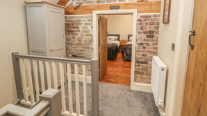 A staircase leading to a loft bedroom with exposed brick walls, a skylight, and a "Please Mind Your Head" sign. - The Old Coach House (Mold)
