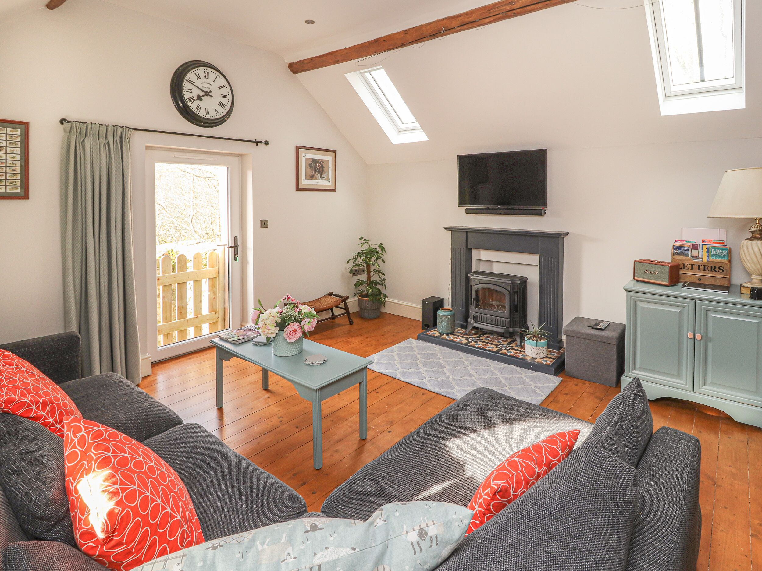 A cozy living room with a fireplace, a sofa set, a dining table, and a TV mounted on the wall.