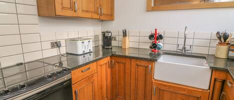 A kitchen with wooden cabinets, a stove, a toaster, a coffee maker, and a sink.