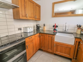 A kitchen with wooden cabinets, a stove, a toaster, a coffee maker, and a sink.