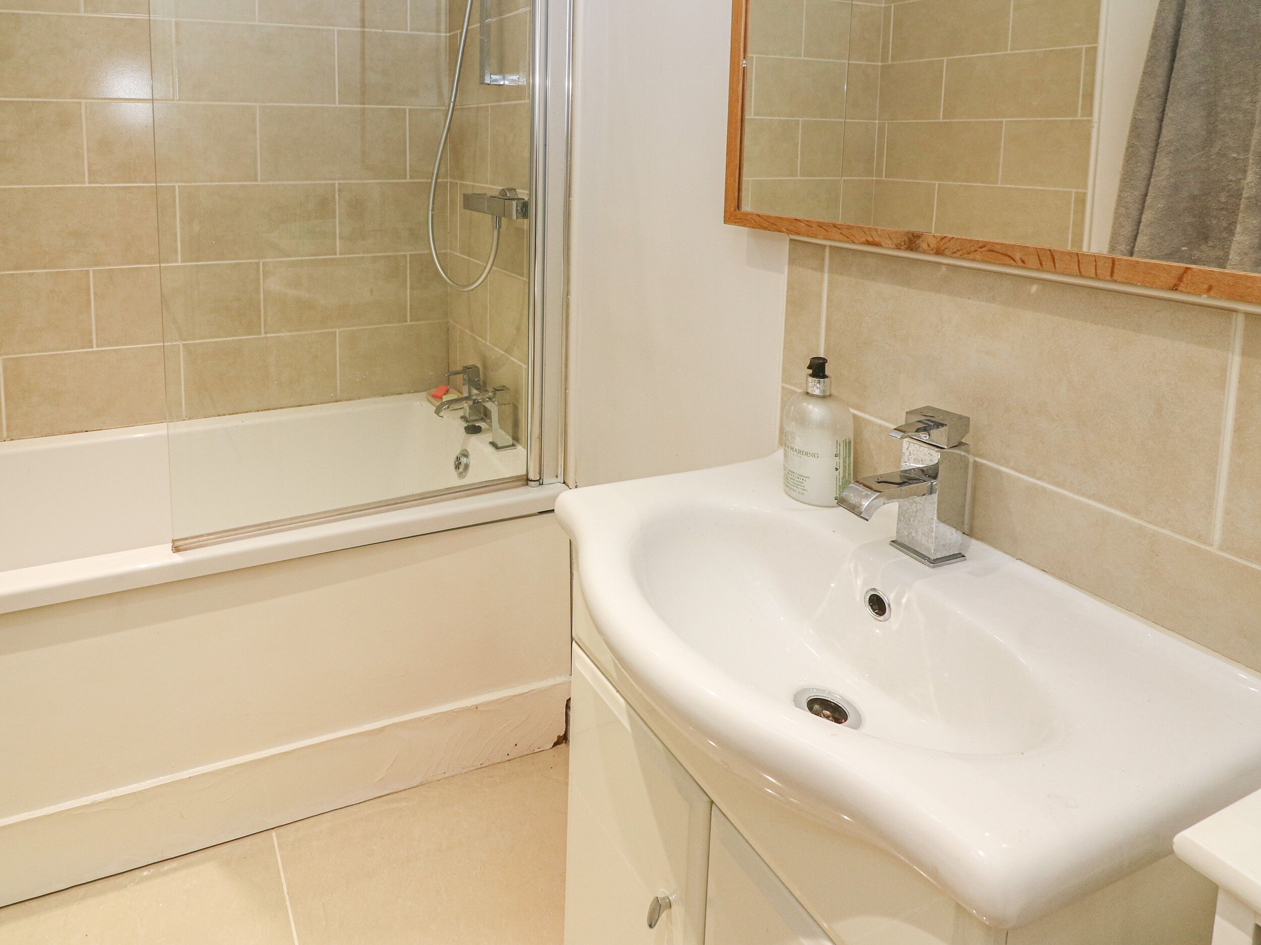 A bathroom with a bathtub, a sink, and a mirror.