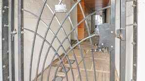 A metal gate with a 'PRIVATE' sign, a wooden ceiling, and a stone floor. - Flat 2 Galloway House (Kendal)