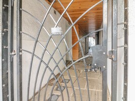 A metal gate with a 'PRIVATE' sign, a wooden ceiling, and a stone floor.