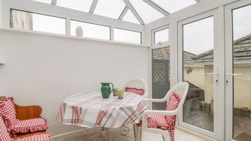 A conservatory with a table and chairs, a green pitcher, and a checkered tablecloth.