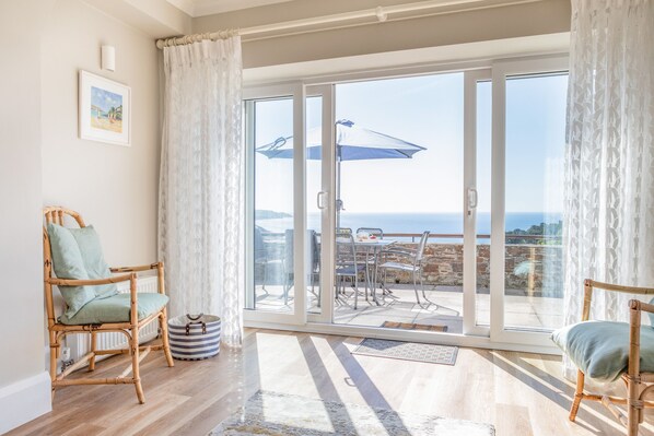 A spacious balcony with a view of the sea, furnished with wicker chairs and a table.