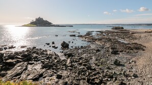 Una costa rocosa con una isla distante y mar tranquilo.