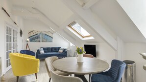 Un loft moderno con techo alto, tragaluces y una zona de estar acogedora con una mesa redonda.