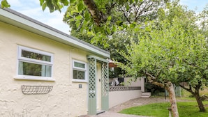 A single-story building with a green door, a small porch, and a gravel pathway leading to the entrance. - The Roost (Camborne)