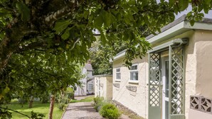 A pathway leading to a house with a small garden and a tree in the foreground. - The Roost (Camborne)