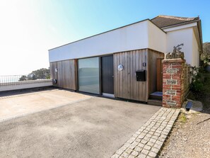 A modern building with a flat roof, large sliding glass doors, and a brick pillar. - Courtenay Villa (Salcombe)