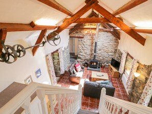 A cozy interior with a stone fireplace, wooden beams, and a staircase. - Melin Bach (Garndolbenmaen)