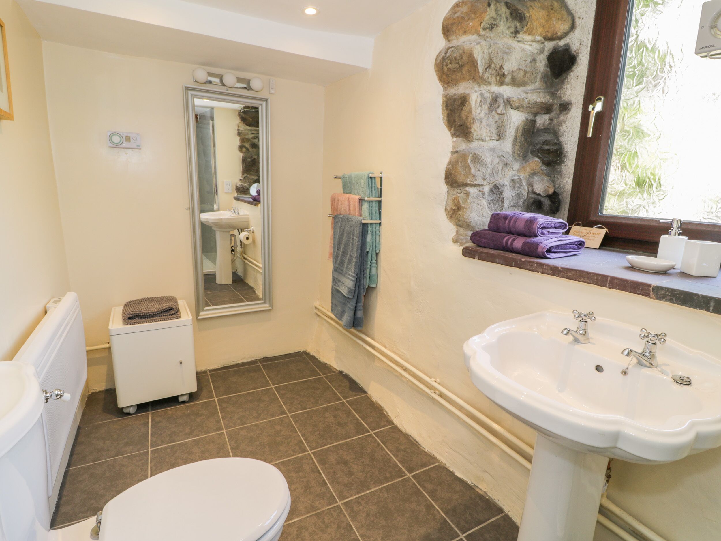 A bathroom with a toilet, sink, and a mirror.