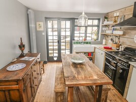 Una cocina con una mesa de madera, armarios, estufa y ventana con vistas.