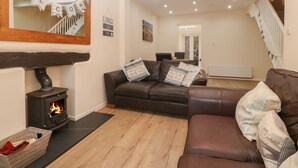 A cozy living room with a fireplace, leather sofas, and a wooden floor. - Castell (Pwllheli)