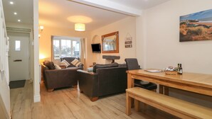 A cozy living room with a sofa, a wooden dining table, and a bench. - Castell (Pwllheli)