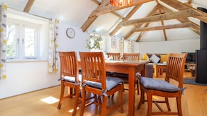 Comedor con mesa y sillas de madera, lámpara colgante y vistas al exterior a través de una ventana.