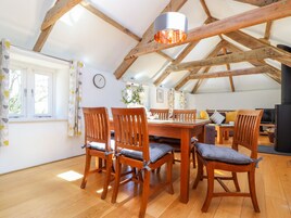 A dining area with a wooden table and chairs, a hanging light fixture, and a view of the outdoors through a window.