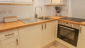 Une cuisine moderne avec des meubles blancs, un évier en acier inoxydable, un four Bosch et un plan de travail en bois.
