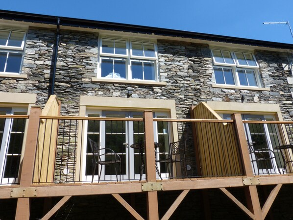 A stone building with multiple windows and a wooden deck with metal railings. - Frost (Ambleside)