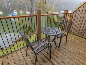A balcony with a metal table and chairs, overlooking a lake with boats. - Frost (Ambleside)