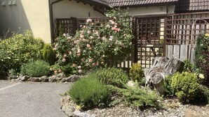 A traditional house with a wooden fence, a rose bush, and a stone pathway. - Stable Cottage (Winscombe)