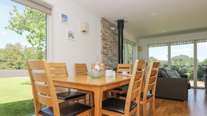 A dining area with a wooden table and chairs, a stone wall, and a view of the outdoors. - Willow (Truro)