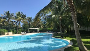 Una piscina con sillas de descanso y palmeras.