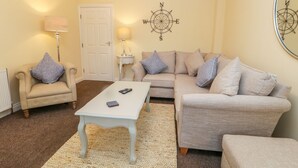 A cozy living room with a beige sofa, armchairs, a white coffee table, and a rug. - Valiant House (Scarborough)