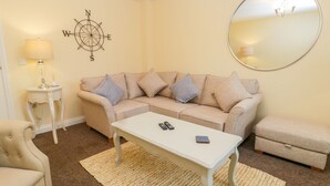A living room with a beige sofa, a white coffee table, a round mirror, and a compass wall decoration. - Valiant House (Scarborough)