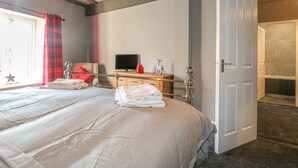 A hotel room with a bed, a desk with a computer, a chair, and a bathroom door. - Royal Oak (Matlock)
