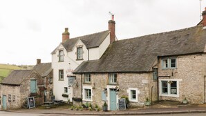 A row of stone buildings with a pub named "The Miners Arms" featuring a traditional pub sign, outdoor seating, and a stone facade. - Royal Oak (Matlock)
