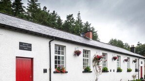 A white building with a red door, labeled "Beltrim National School 1899".