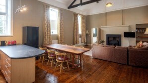 A spacious living area with a wooden dining table, chairs, a sofa, and a fireplace.