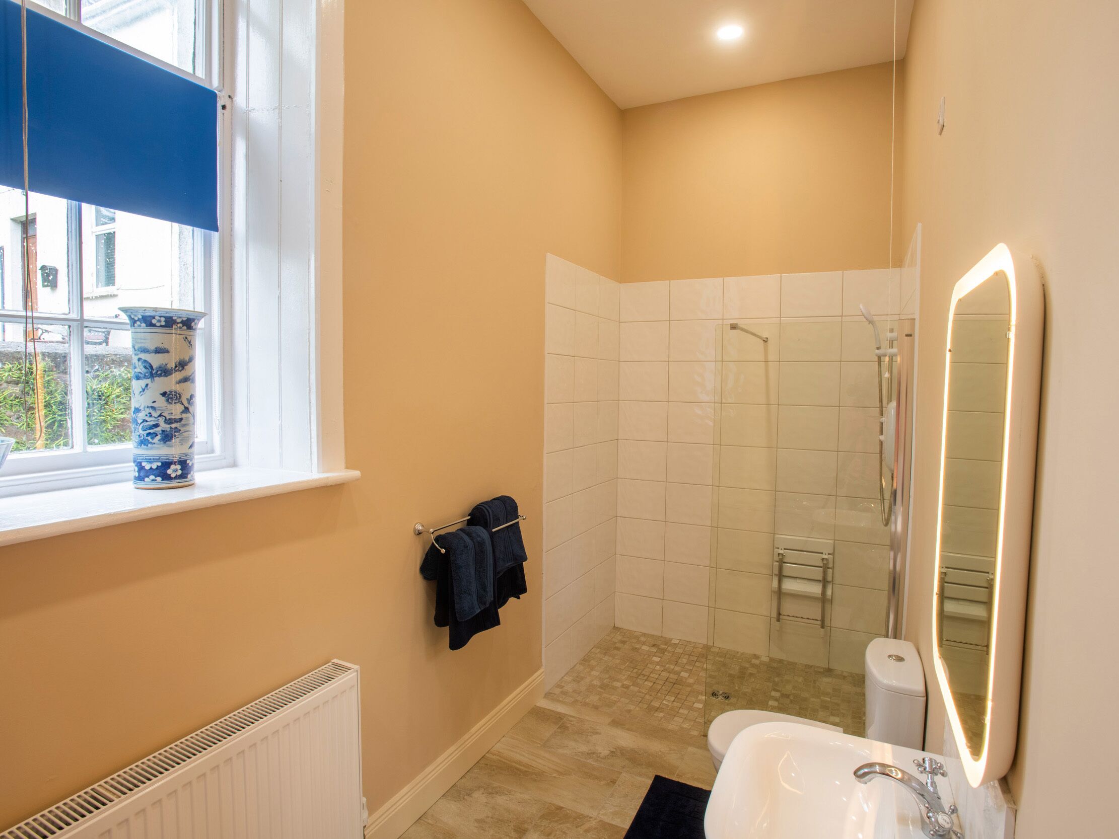 A bathroom with a window, a shower, a toilet, and a sink.