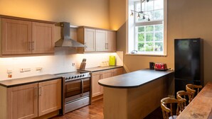 A modern kitchen with wooden cabinets, a stainless steel stove, and a black refrigerator.