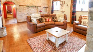 A cozy living room with a leather sofa, a wooden coffee table, and a patterned rug. - Woodland Lodge (Alfreton)