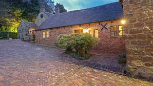 A traditional brick building with a stone wall, a paved driveway, and a small garden area. - Woodland Lodge (Alfreton)