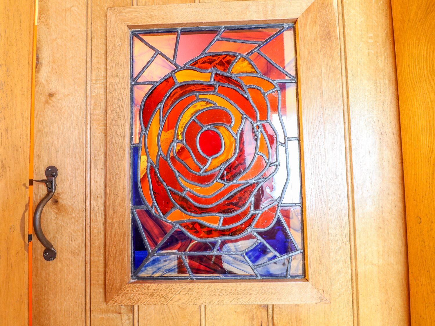 A wooden door with a stained glass window depicting a rose.