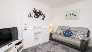 Ein Wohnzimmer mit Fernseher, Sofa und einem Kunstwerk an der Wand.