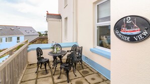 Eine Terrasse mit Tisch und Stühlen, einem Schild mit Schiffsdekor und Blick auf das Meer.
