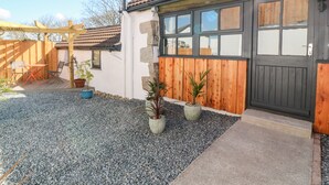 A house with a tiled roof, a wooden door, and a gravel driveway. - Toadstools (Helston)