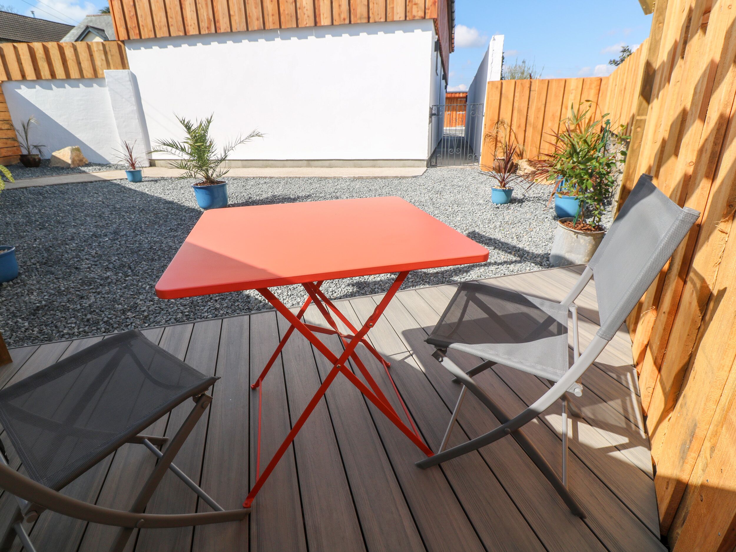Een houten terras met een rode tafel en twee stoelen.