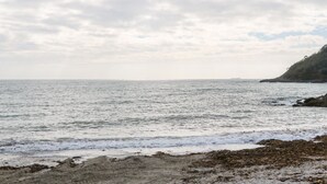 A coastal scene with a sandy beach and rocky outcrops. - Toadstools (Helston)