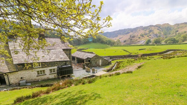 A stone farmhouse with a stone wall and a small garden area. - Tilberthwaite Farm Cottage (Coniston)