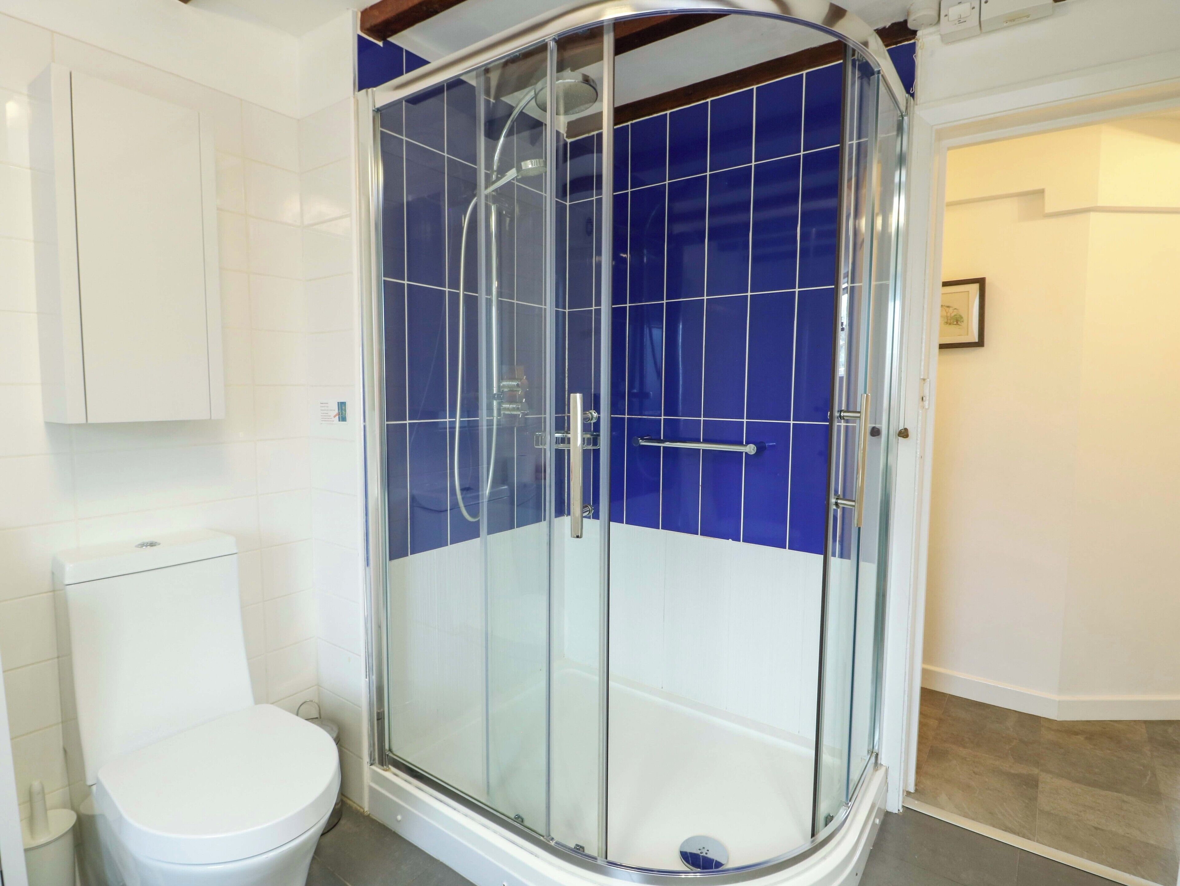 A bathroom with a glass-enclosed shower, a toilet, and a sink.