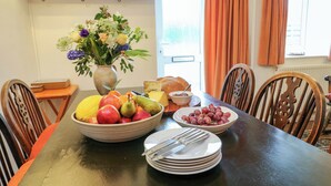 Una tavola imbandita con frutta, un piatto di formaggi e un vaso di fiori.