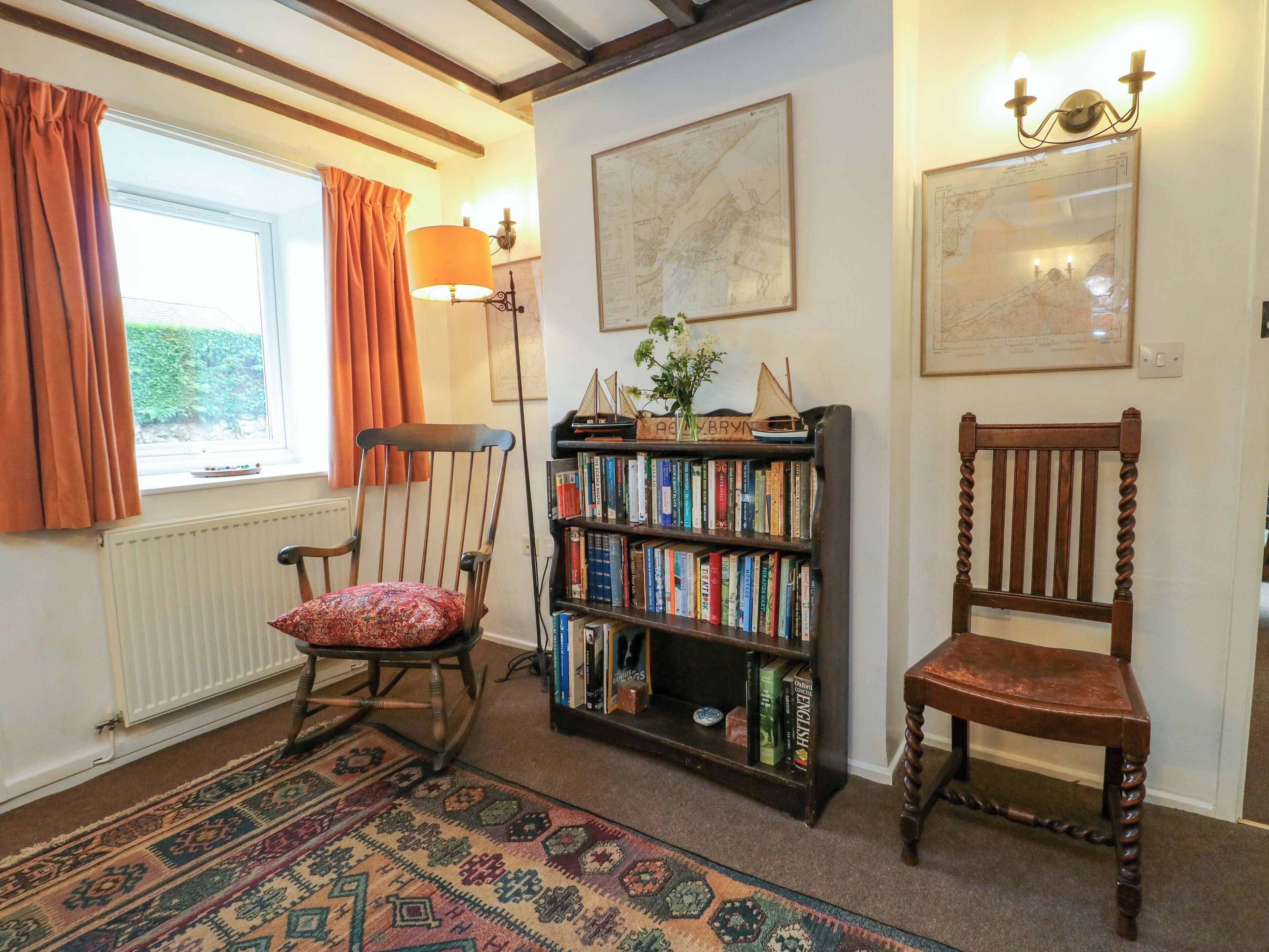 A cozy room with a rocking chair, a bookshelf, and a patterned rug.