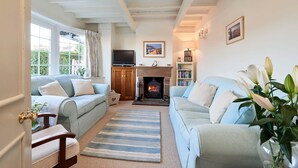 A cozy living room with two sofas, a fireplace, a bookshelf, and a television. - Rigg Cottage (Whitby)