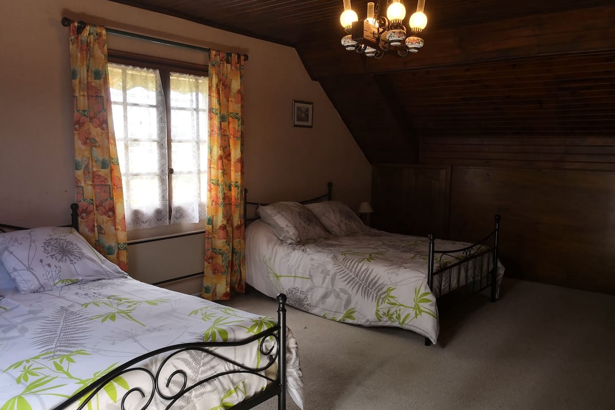 Een slaapkamer met twee bedden, een houten plafond en een kroonluchter.